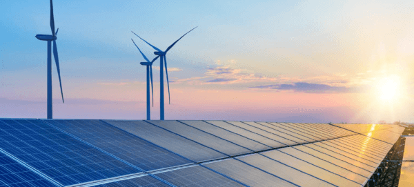 Wind turbines and solar panels against a setting sun